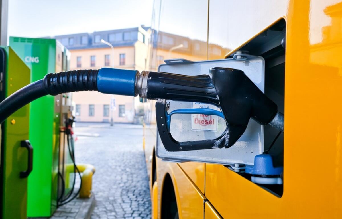 Diesel fuel nozzle inserted into a yellow van's fuel tank at a station