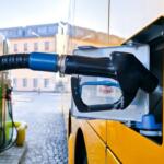 Diesel fuel nozzle inserted into a yellow van's fuel tank at a station