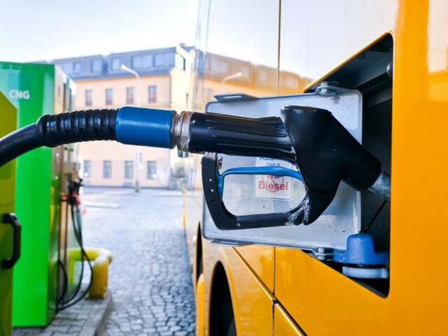 Diesel fuel nozzle inserted into a yellow van's fuel tank at a station