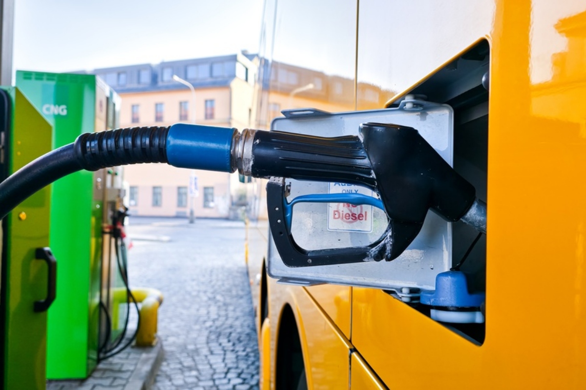 Diesel fuel nozzle inserted into a yellow van's fuel tank at a station