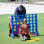 Gov. JB Pritzker plays Connect 4 with children following an event to open a new sports park in Springfield on April 28, 2026. (Capitol News Illinois photo by Jerry Nowicki)