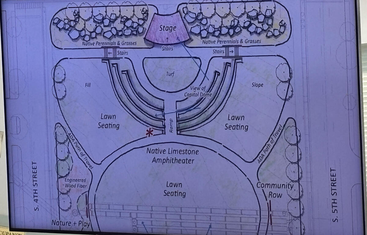 Architectural plan of an outdoor amphitheater with a central stage and two lawn seating areas.