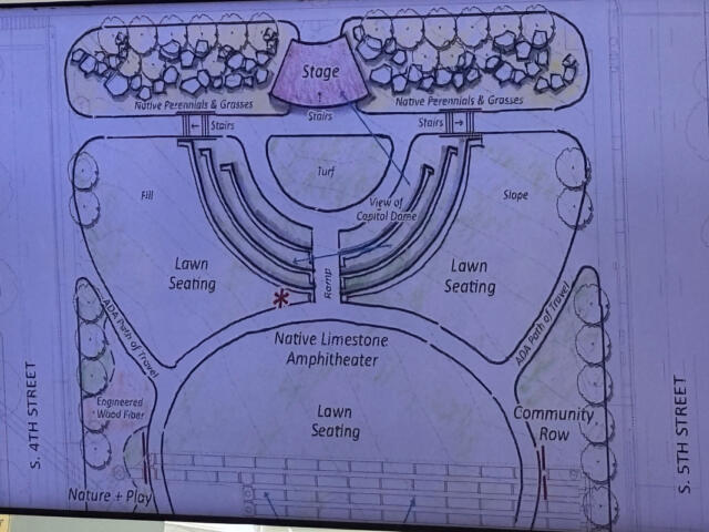 Architectural plan of an outdoor amphitheater with a central stage and two lawn seating areas.