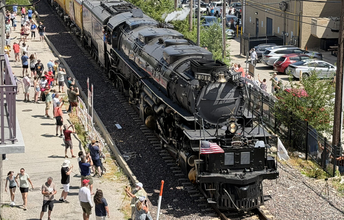 Steam locomotive 4014 on the tracks beside a crowded platform, with people taking photos and waving.