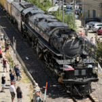 Steam locomotive 4014 on the tracks beside a crowded platform, with people taking photos and waving.