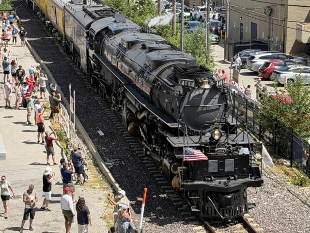 Steam locomotive 4014 on the tracks beside a crowded platform, with people taking photos and waving.