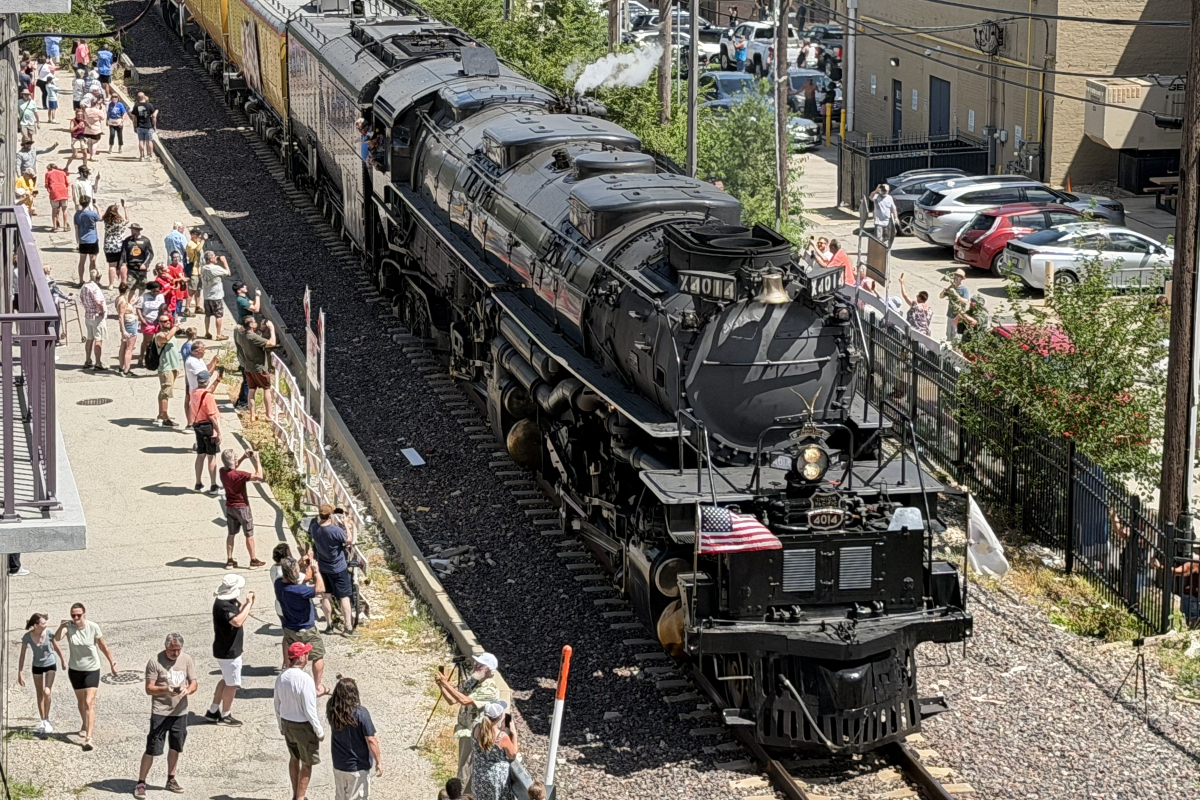 Steam locomotive 4014 on the tracks beside a crowded platform, with people taking photos and waving.