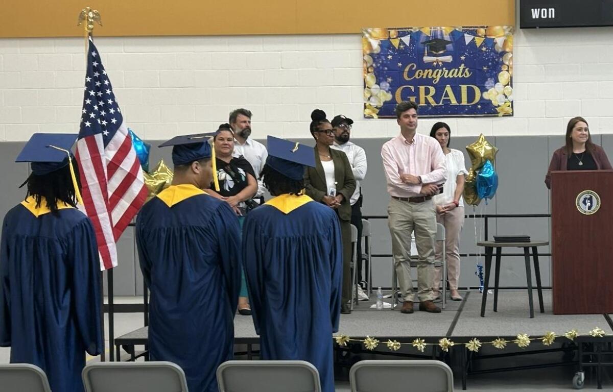 Traci Kinsley (at podium), principal of the high school at Monarch Youth Center, speaks to the graduates Monday, June 29.
