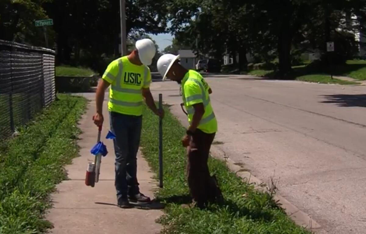 Workers with USIC identify areas for fiber optic lines while trying to beat the heat.