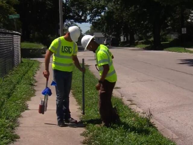 Workers with USIC identify areas for fiber optic lines while trying to beat the heat.