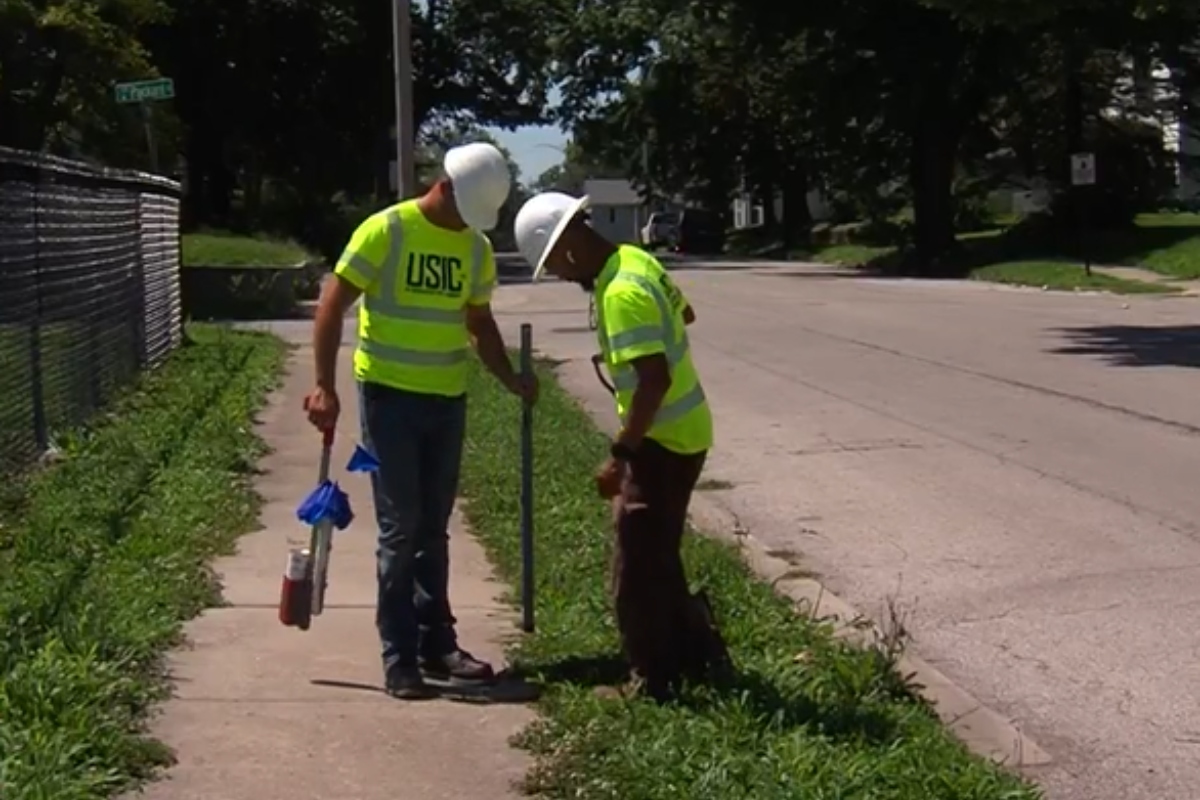 Workers with USIC identify areas for fiber optic lines while trying to beat the heat.