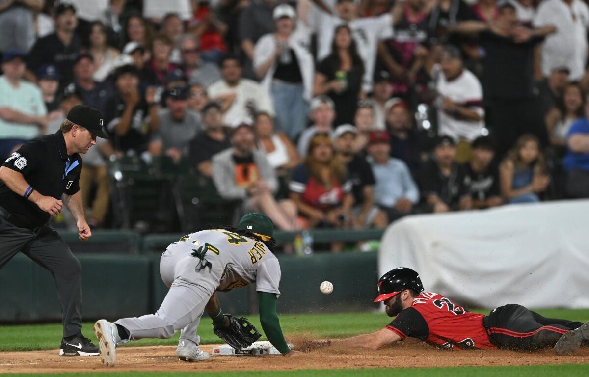 Chicago White Sox's Tristan Peters, right, slides safely into third base for an RBI triple while Athletics third baseman Joshua Kuroda-Grauer, center, catches the throw during the seventh inning of a baseball game in Chicago, Friday, July 10, 2026. (AP Photo/Paul Beaty)