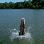A swimmer dives into Cedar Lake during an extreme heat warning Monday, July 13, 2026, in Minneapolis. (AP Photo/Ellen Schmidt)