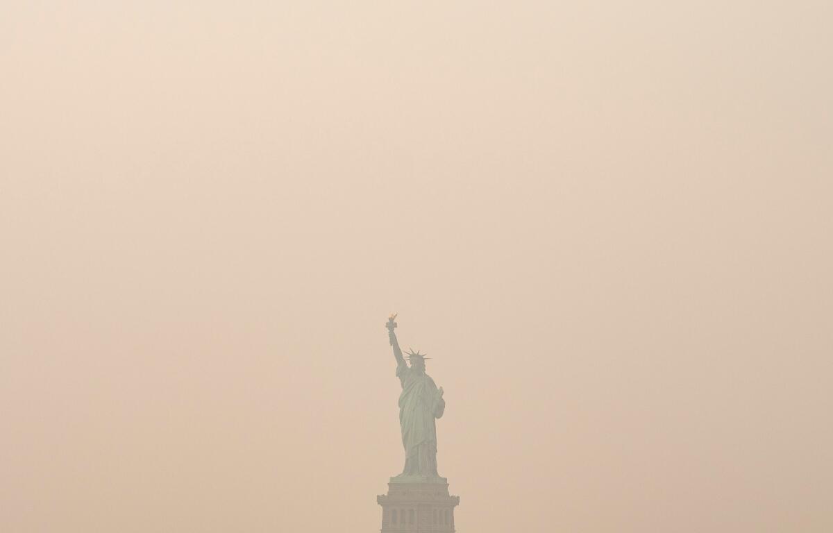 The Statue of Liberty is photographed from the Staten Island Ferry as smoke from wildfires blankets the sky, Thursday, July 16, 2026, in New York. (AP Photo/Yuki Iwamura)