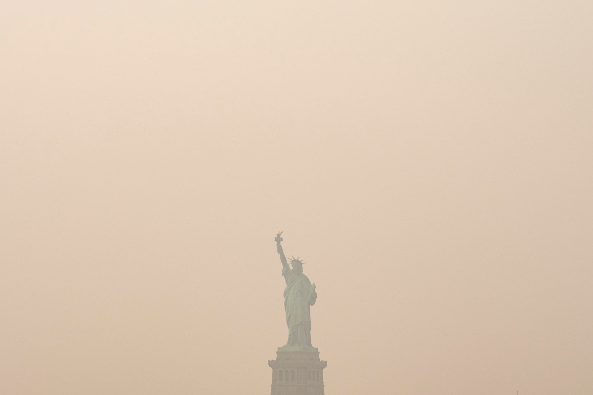 The Statue of Liberty is photographed from the Staten Island Ferry as smoke from wildfires blankets the sky, Thursday, July 16, 2026, in New York. (AP Photo/Yuki Iwamura)