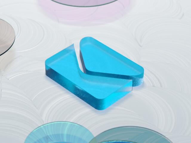 Blue translucent geometric block resting on a white swirled surface with circular reflective discs nearby (decorative image)