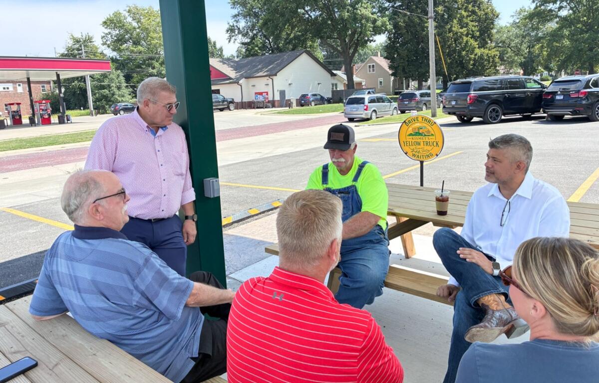 Republican Darren Bailey, standing left, and his running mate, Aaron Del Mar, seated far right, speak with supporters at an event in Nokomis on Monday, Aug. 24, 2026. (Capitol News Illinois photo by Ben Szalinski)