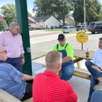 Republican Darren Bailey, standing left, and his running mate, Aaron Del Mar, seated far right, speak with supporters at an event in Nokomis on Monday, Aug. 24, 2026. (Capitol News Illinois photo by Ben Szalinski)