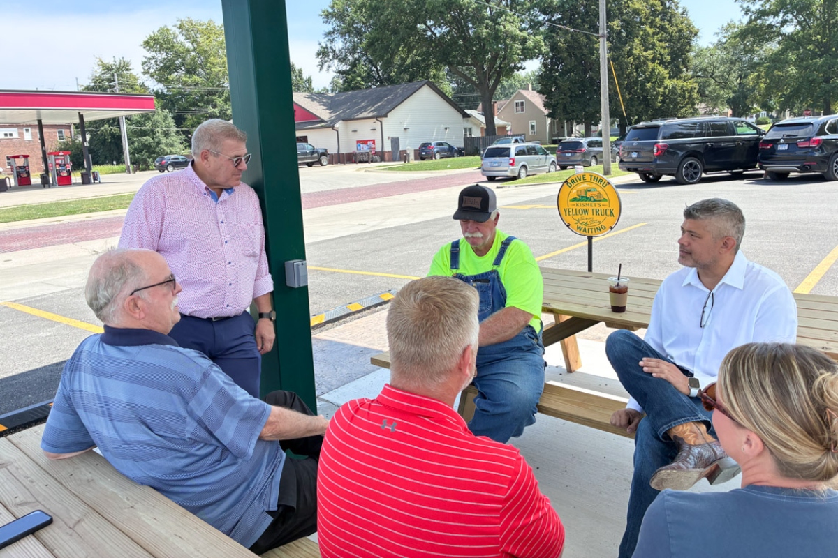 Republican Darren Bailey, standing left, and his running mate, Aaron Del Mar, seated far right, speak with supporters at an event in Nokomis on Monday, Aug. 24, 2026. (Capitol News Illinois photo by Ben Szalinski)