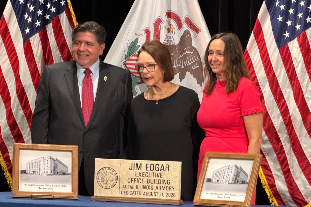 Governor JB Pritzker, widow Brenda Edgar, and daughter Elizabeth, pose in front of plaques and a hand-made sign to be placed at the Illinois Armory, now the Jim Edgar Executive Office Building.