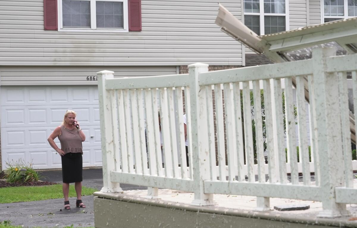 Kerry Hourigan speaks on the phone after reviewing damage a storm caused to her home in Tinley Park, Ill., Tuesday, Aug. 11, 2026. (AP Photo/Laura Bargfeld)