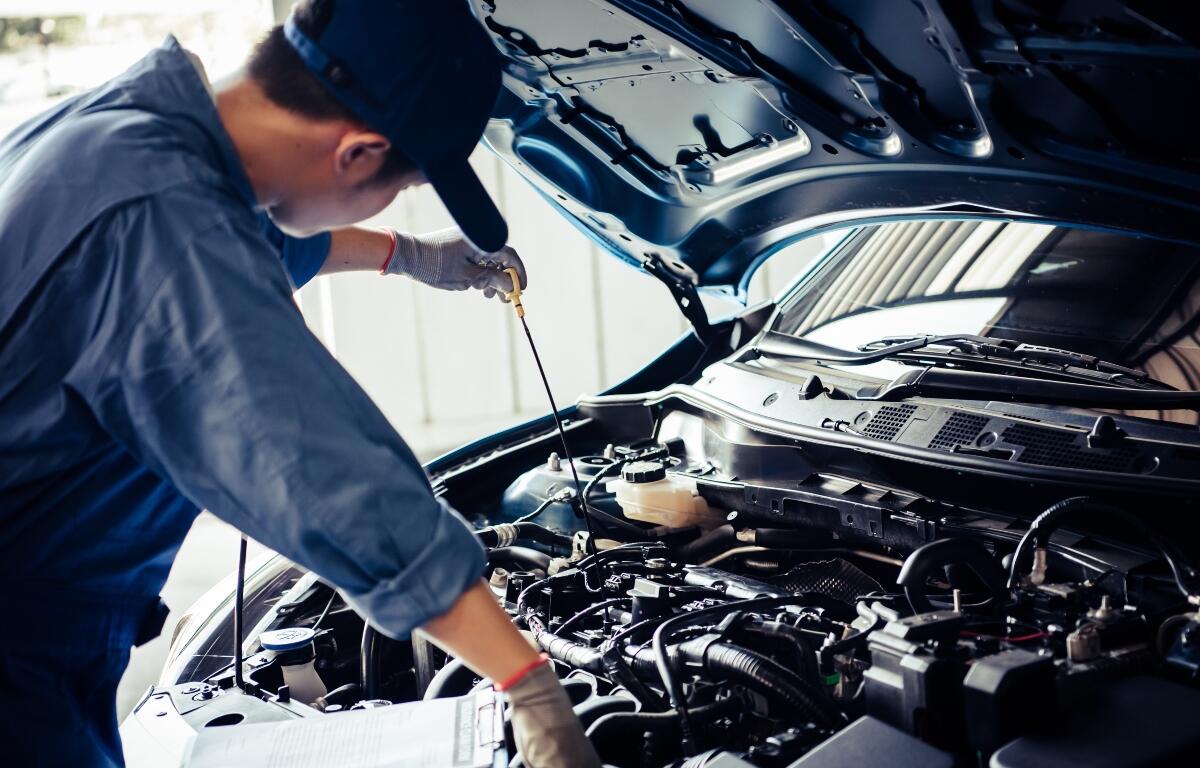Car mechanic holding checking gear oil to maintenance vehicle by customer claim order in auto repair shop garage. Engine repair service. People occupation and business job. Automobile technician