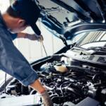 Car mechanic holding checking gear oil to maintenance vehicle by customer claim order in auto repair shop garage. Engine repair service. People occupation and business job. Automobile technician