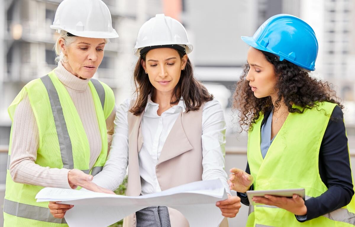 Engineering, women or blueprint for construction site, teamwork or architecture with conversation. Group, staff or leader with employees, documents or floor plan with contractor, review or industrial