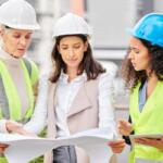 Engineering, women or blueprint for construction site, teamwork or architecture with conversation. Group, staff or leader with employees, documents or floor plan with contractor, review or industrial