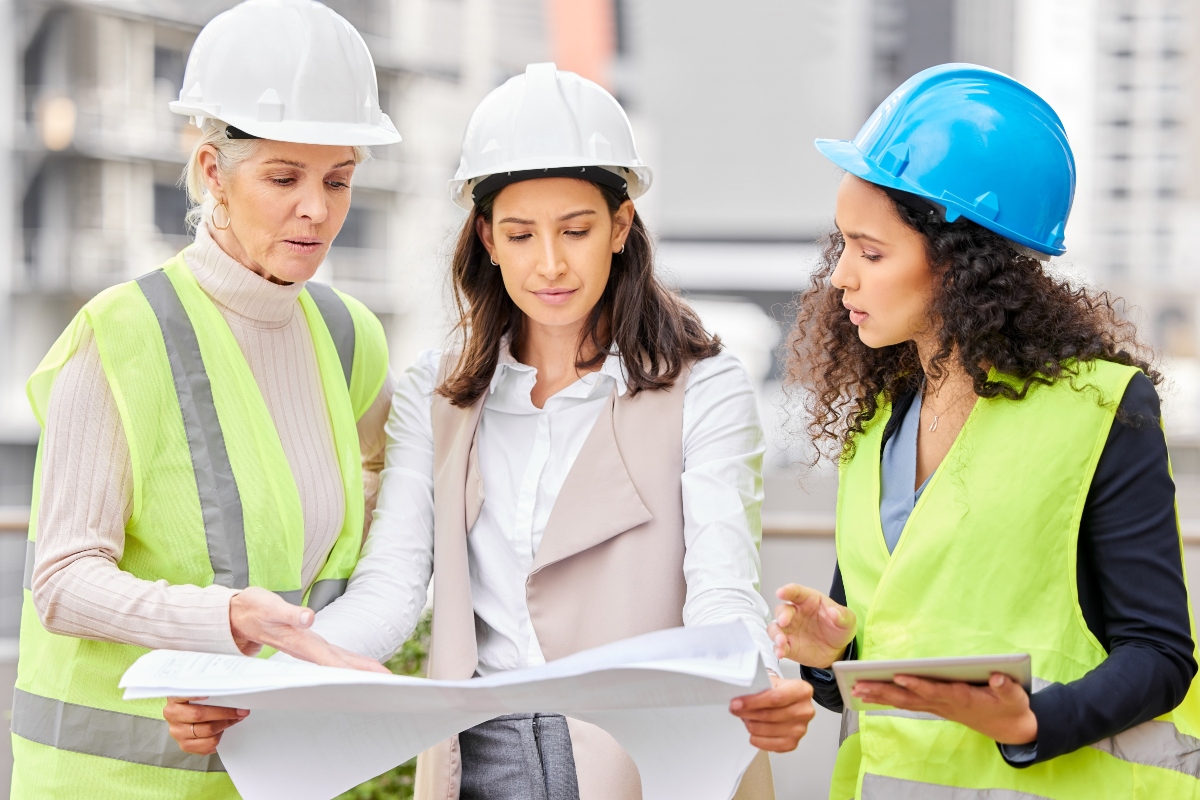 Engineering, women or blueprint for construction site, teamwork or architecture with conversation. Group, staff or leader with employees, documents or floor plan with contractor, review or industrial