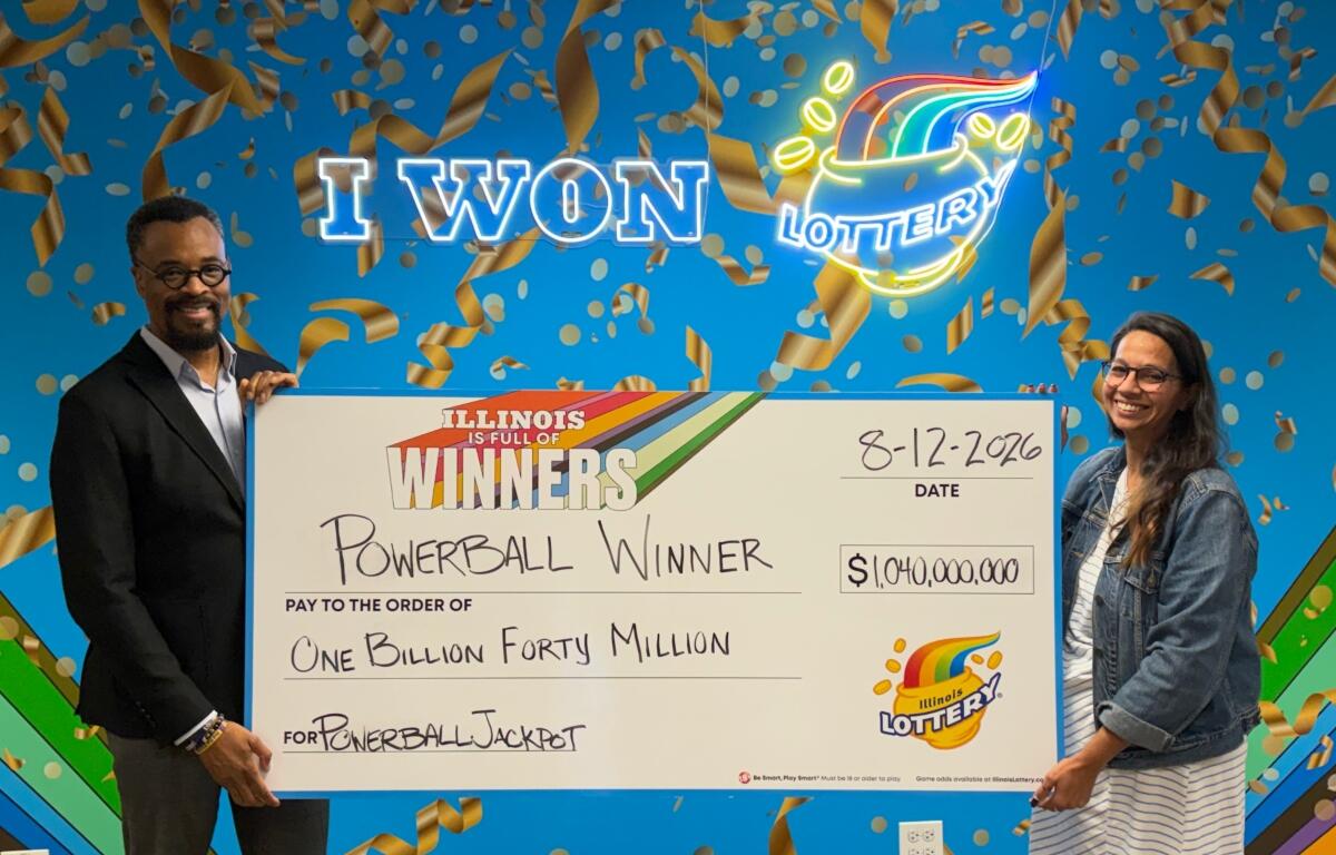 Illinois Lottery Director, Harold Mays (left), and Chicago Prize Center manager Amanda Crosas hold the big check representing the $1.04 billion Powerball jackpot from the August 12 drawing.