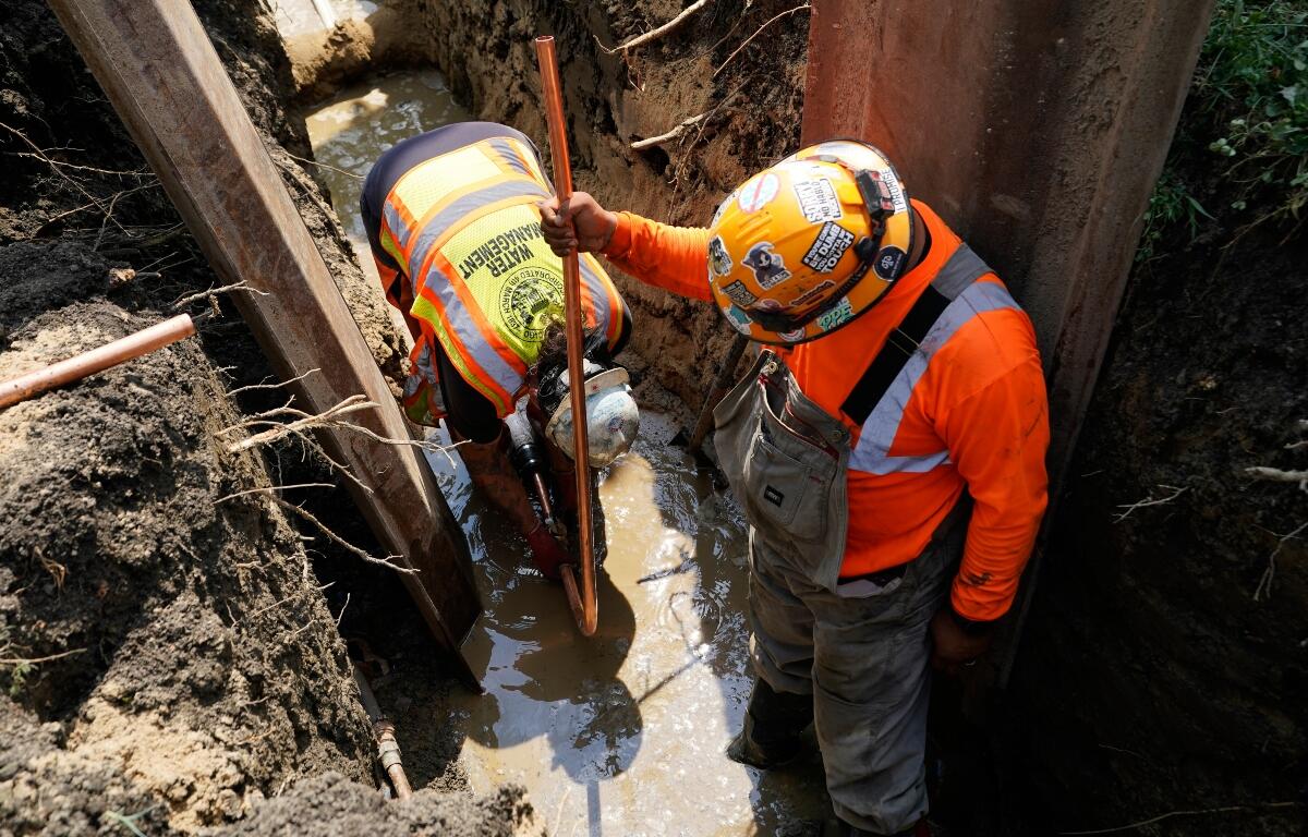 Workers install a copper pipe to replace a lead service line that brings drinking water to homes Tuesday, July 21, 2026, in Chicago. (AP Photo/Alyssa Goodman)