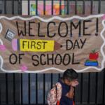 FILE - A student wipes his face while his mother takes a photo of him with a sign on the first day of school at Betsy Ross Elementary School in Anaheim, Calif., on Aug. 6, 2026. (AP Photo/Jae C. Hong, File)