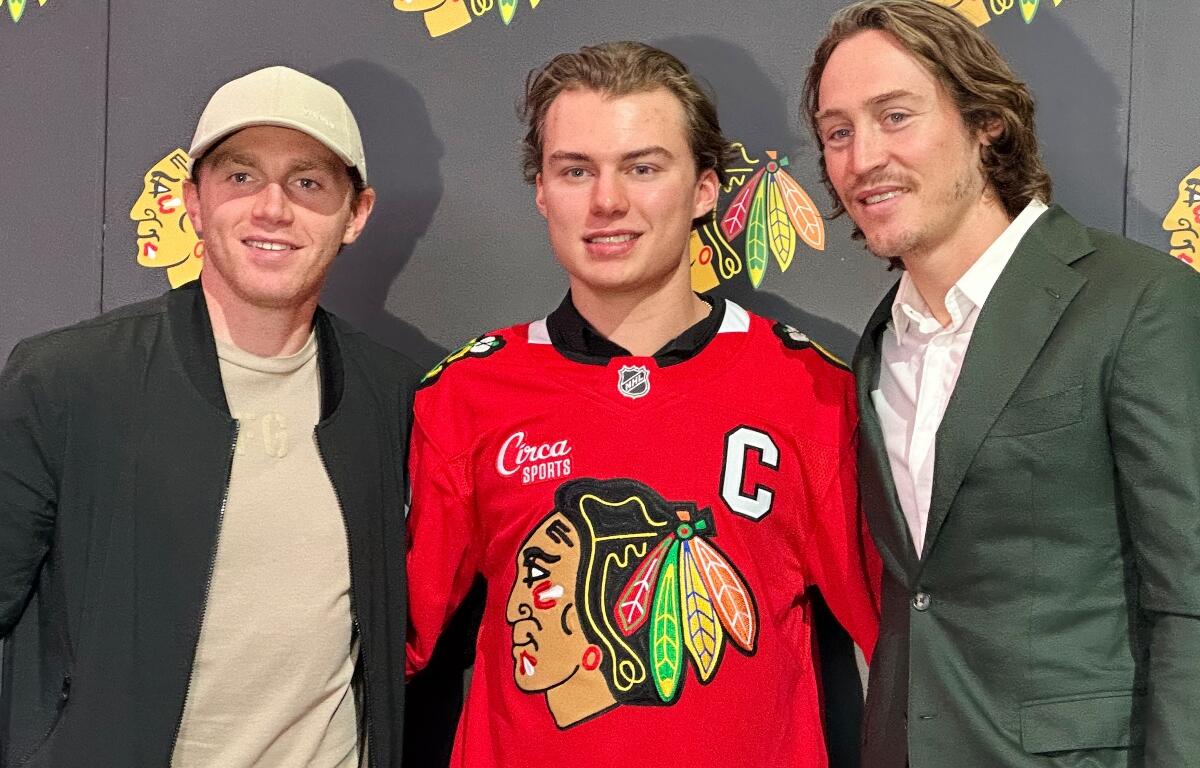 In this photo taken with a smartphone, Chicago Blackhawks players, from left, Patrick Kane, Connor Bedard and Tyler Bertuzzi pose during a news conference introducing Bedard as the new captain of the NHL hockey club, Tuesday, Sept. 15, 2026, in Chicago. (AP Photo/Jay Cohen)
