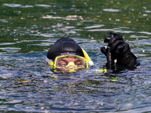 Diver Andrew Lucca lifts his buoyancy control device above the water to let out air and descend into the water April 25, 2026, at Mermet Springs in Belknap, Illinois. (Peyton Cook for the Saluki Local Reporting Lab)