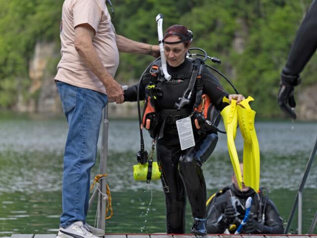 A Great American Diver employee helps owner Heather Kiswani up the stairs after a dive event April 25, 2026, at Mermet Springs in Belknap, Illinois. (Peyton Cook for the Saluki Local Reporting Lab)