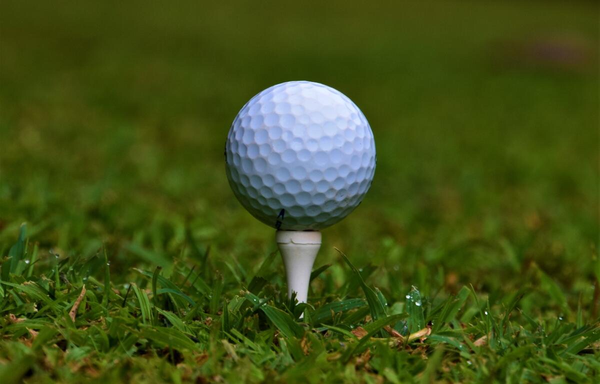 Golf ball on white tee detail closeup golfing