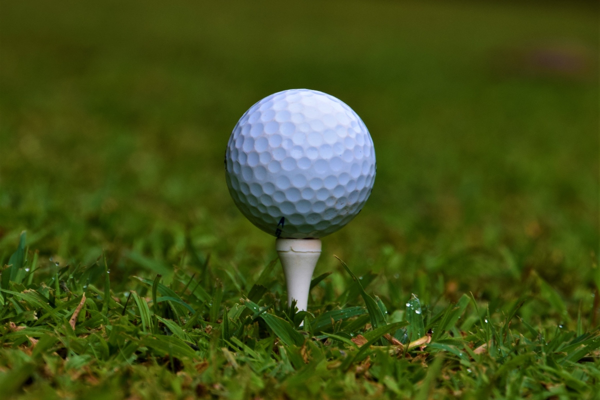 Golf ball on white tee detail closeup golfing