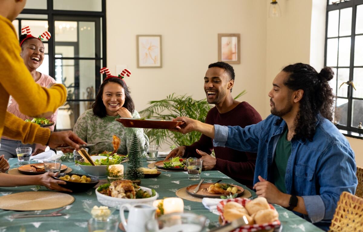 Christmas time, young multiracial friends enjoying festive holiday meal together, at home. celebration, friendship, dining, gathering, happiness, tradition