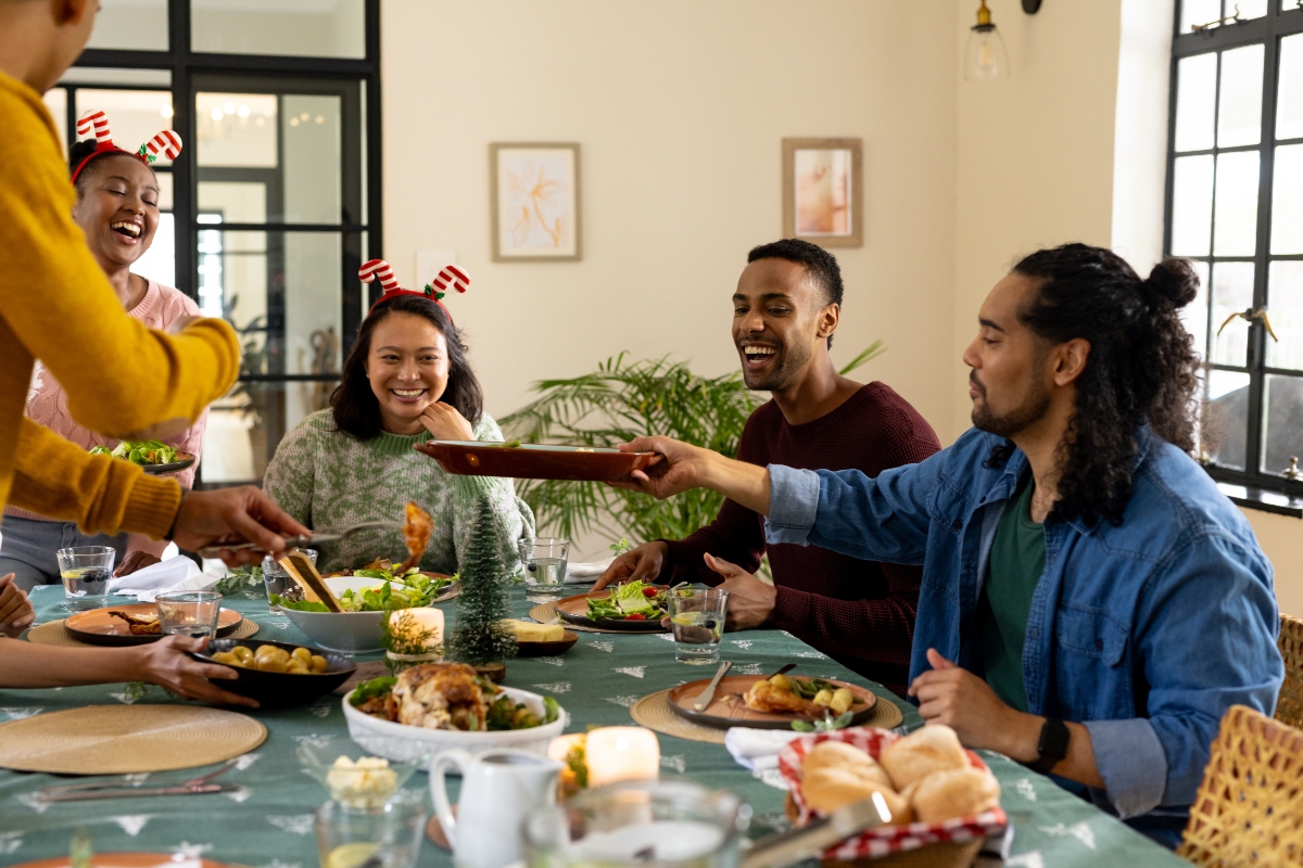 Christmas time, young multiracial friends enjoying festive holiday meal together, at home. celebration, friendship, dining, gathering, happiness, tradition