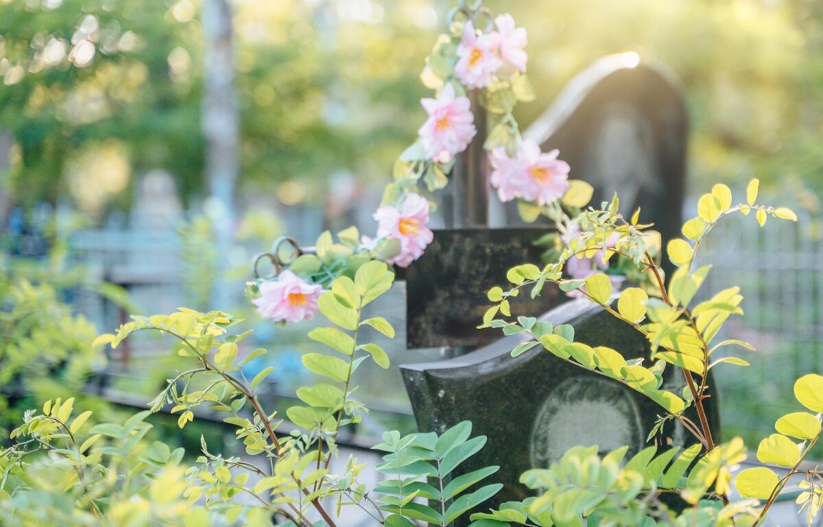 Grave with flowers decorated grave, in cemetery, with grave, flowers, with stone, metal texture, from a close-up perspective, with pink, green accents, and serene respectful mood, clear detail.