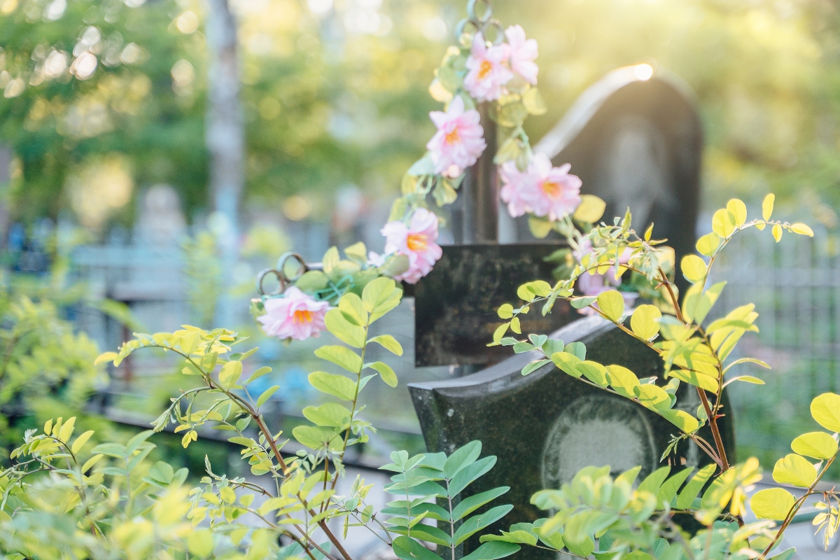 Grave with flowers decorated grave, in cemetery, with grave, flowers, with stone, metal texture, from a close-up perspective, with pink, green accents, and serene respectful mood, clear detail.