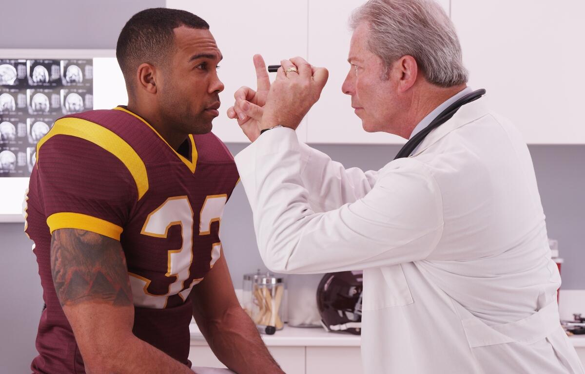 College football player having senior doctor review his concussion injury.