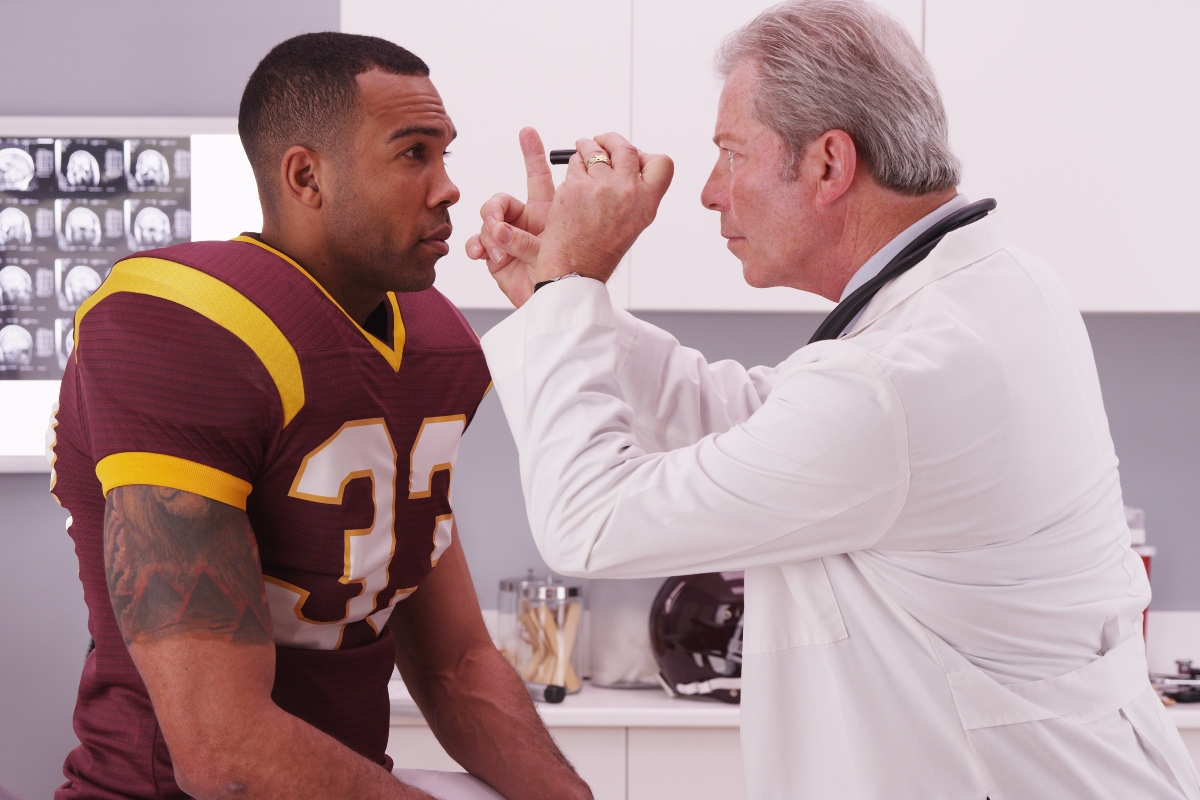 College football player having senior doctor review his concussion injury.