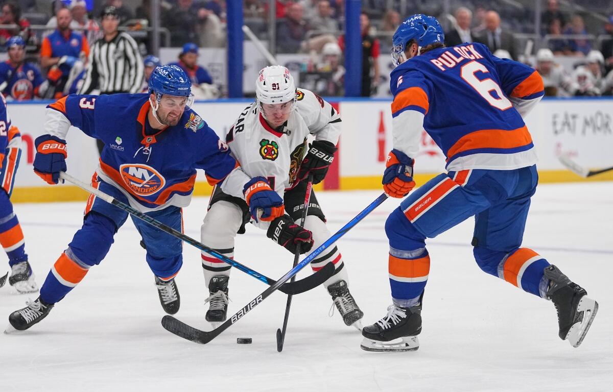 New York Islanders' Adam Pelech (3) and Ryan Pulock (6) fights for control of the puck with Chicago Blackhawks' Frank Nazar (91) during the first period of an NHL hockey game Thursday, Oct. 8, 2026, in Elmont, N.Y. (AP Photo/Frank Franklin II)