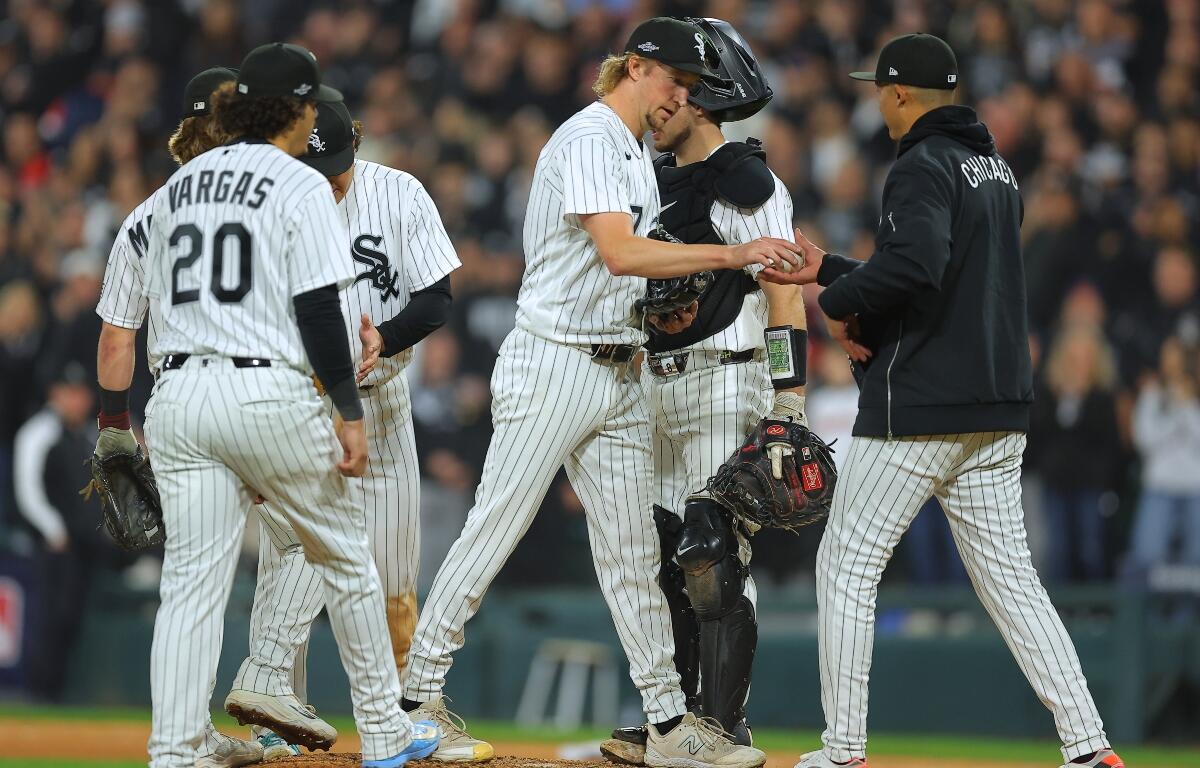 Chicago White Sox relief pitcher Erick Fedde, middle, hands the game ball to manager Will Venable, right, for a pitching change during the fifth inning of Game 4 of baseball's American League Division Series against the Cleveland Guardians, Thursday, Oct. 8, 2026, in Chicago. (AP Photo/Melissa Tamez)