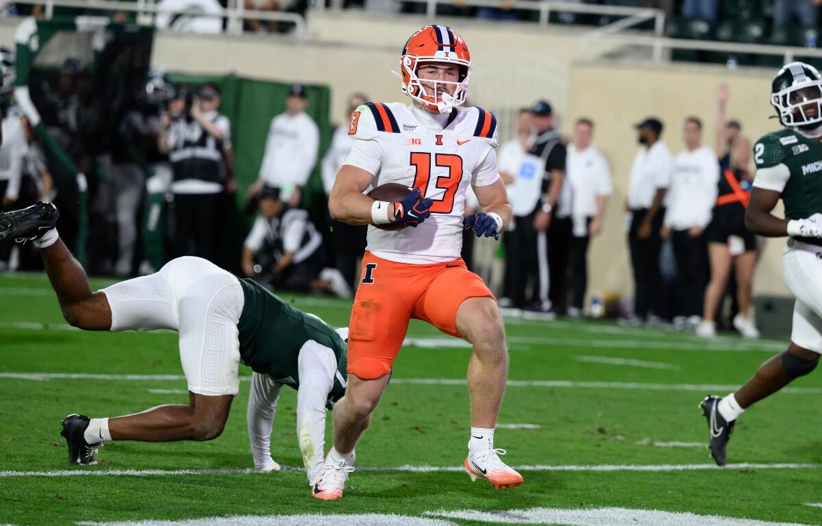Illinois wide receiver Hudson Clement (13) scores on a touchdown pass against Michigan State on the first play of overtime during an NCAA college football game, Saturday, Oct. 10, 2026, in East Lansing, Mich. (AP Photo/Lon Horwedel)