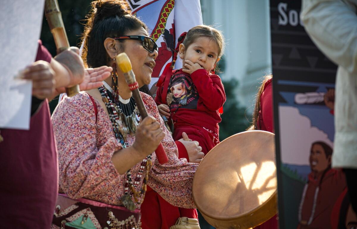 Sacramento, CA, U.S.A. - FEB. 13, 2024: A woman drums and sings during a song at the Missing and Murdered Indigenous Peoples Day of Action at the state capitol.